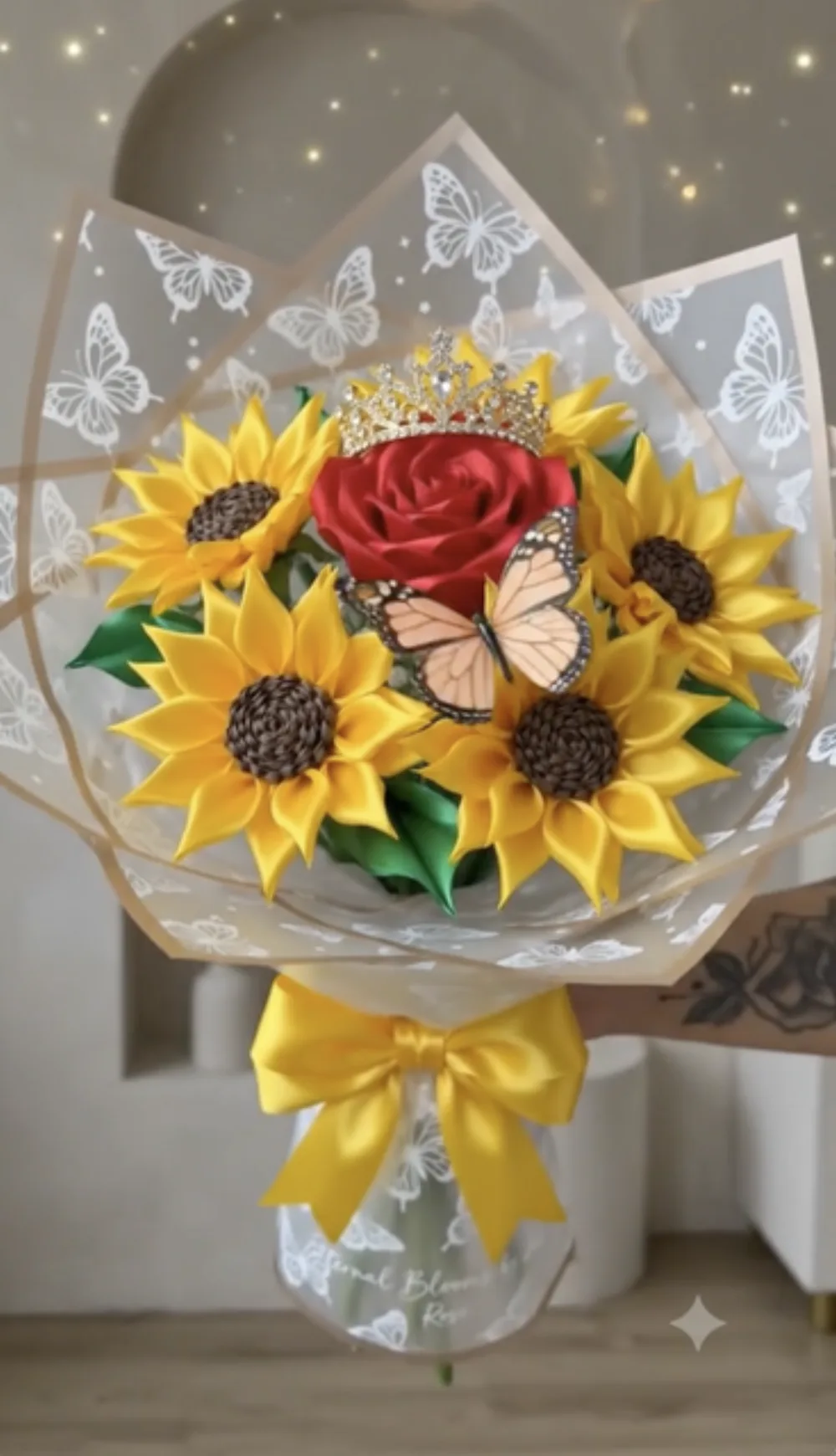 Wrapped bouquet with a crowned red satin rose surrounded by satin sunflowers and a monarch butterfly